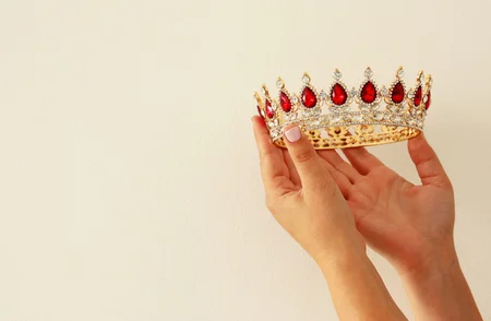 92264550-mano-de-mujer-sosteniendo-una-corona-para-mostrar-la-victoria-o-ganar-el-primer-lugar-fondo-blanco-c