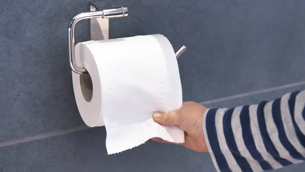 una-persona-coge-papel-higienico-de-un-portarrollos