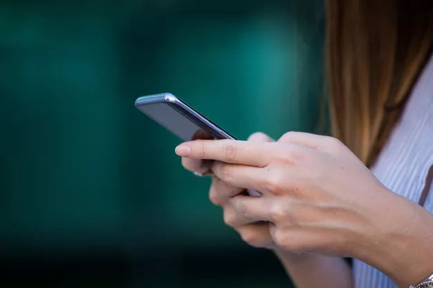 cierre-arriba-manos-mujeres-que-sostienen-telefono-celular-pantalla-blanco-mensajes-texto-o-contenido-promocional_1212-1279